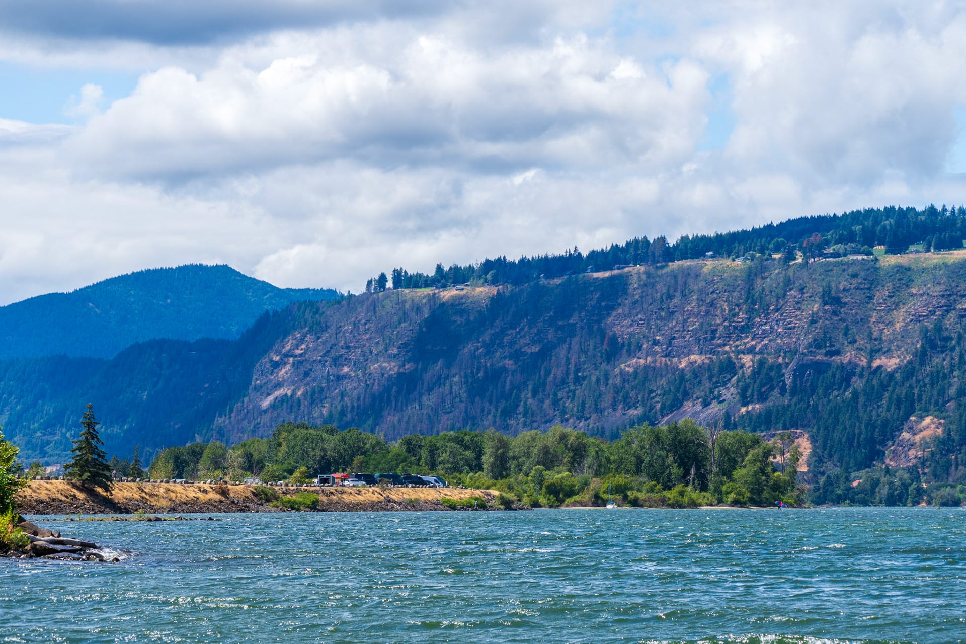 A wide view of the Columbia River Gorge, blue water below basalt walls and stacked cloud.