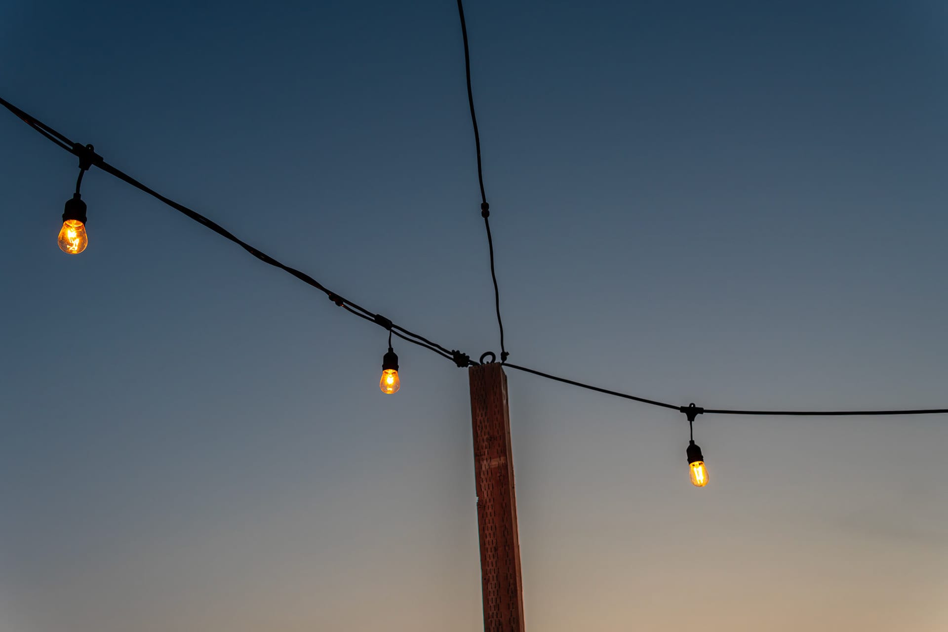 String lights strung between poles against a dusk sky.