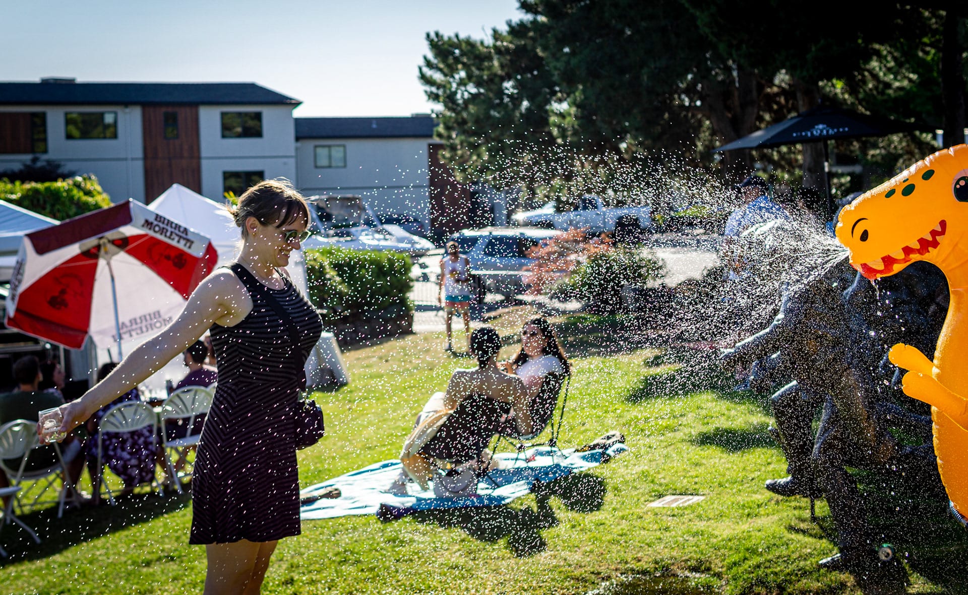 A backyard party with umbrellas and an inflatable water slide, houses behind.