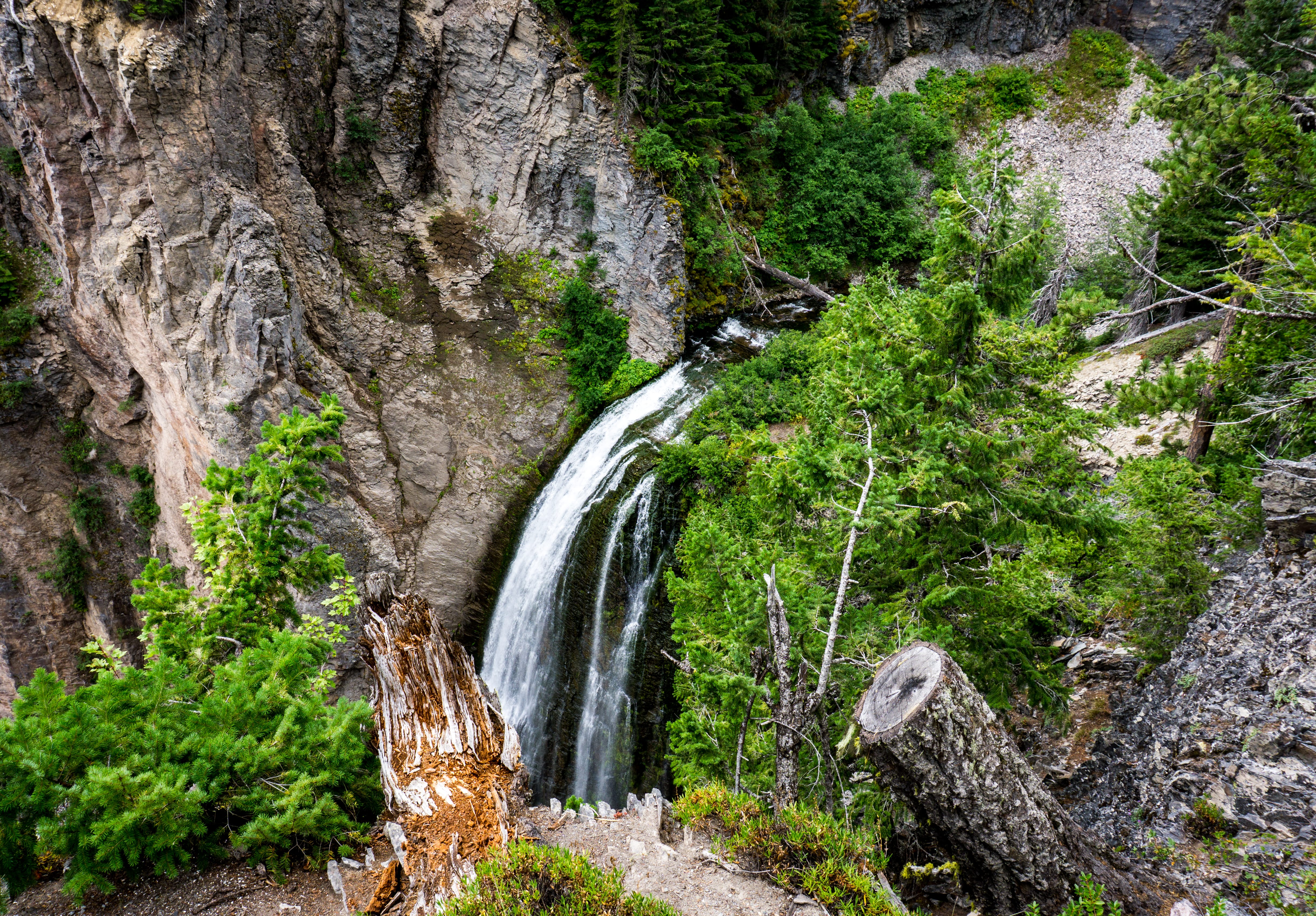 A narrow waterfall drops through a rocky, forested canyon.