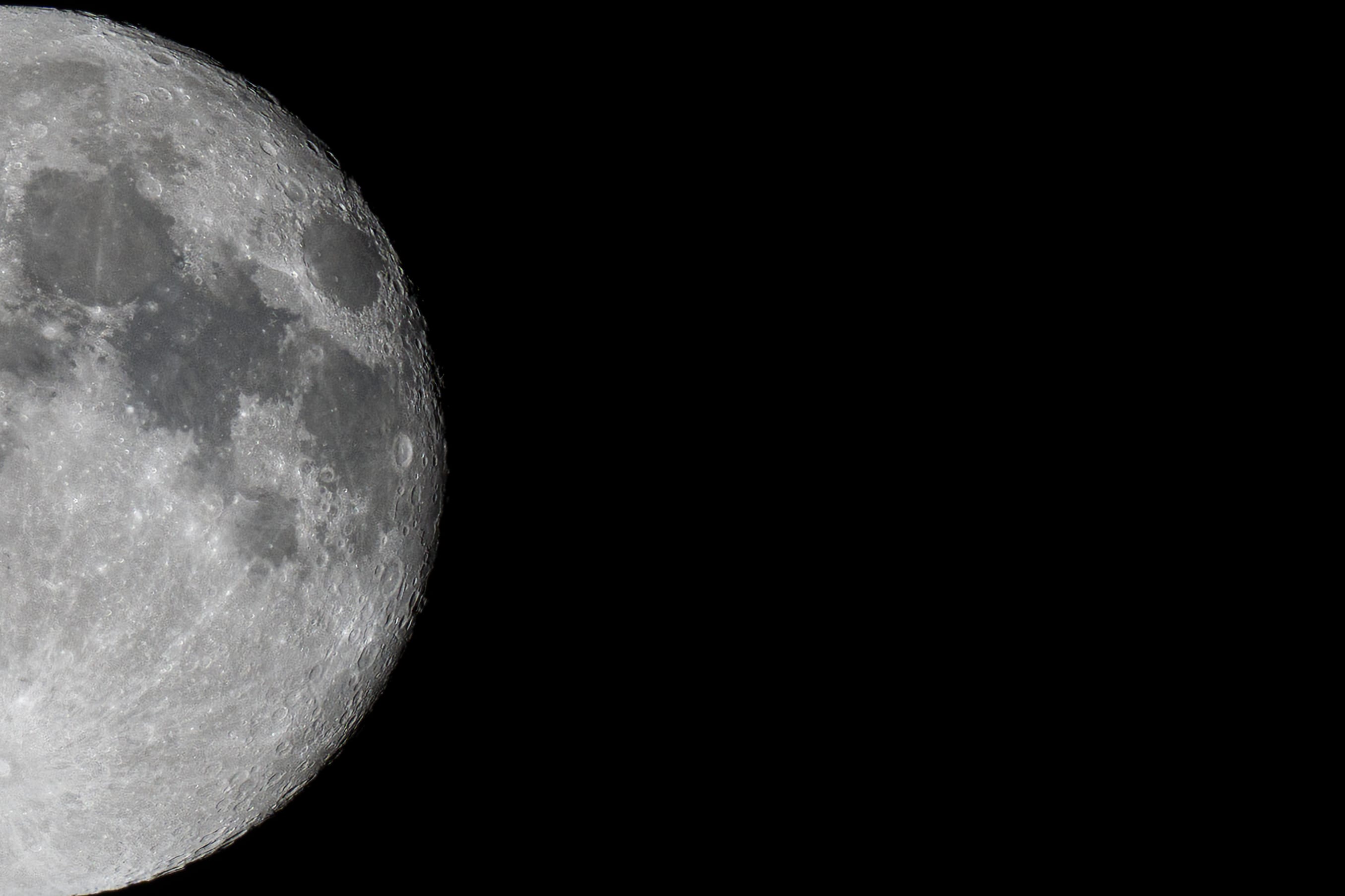 A detailed partial moon fills the left side of a black night sky.