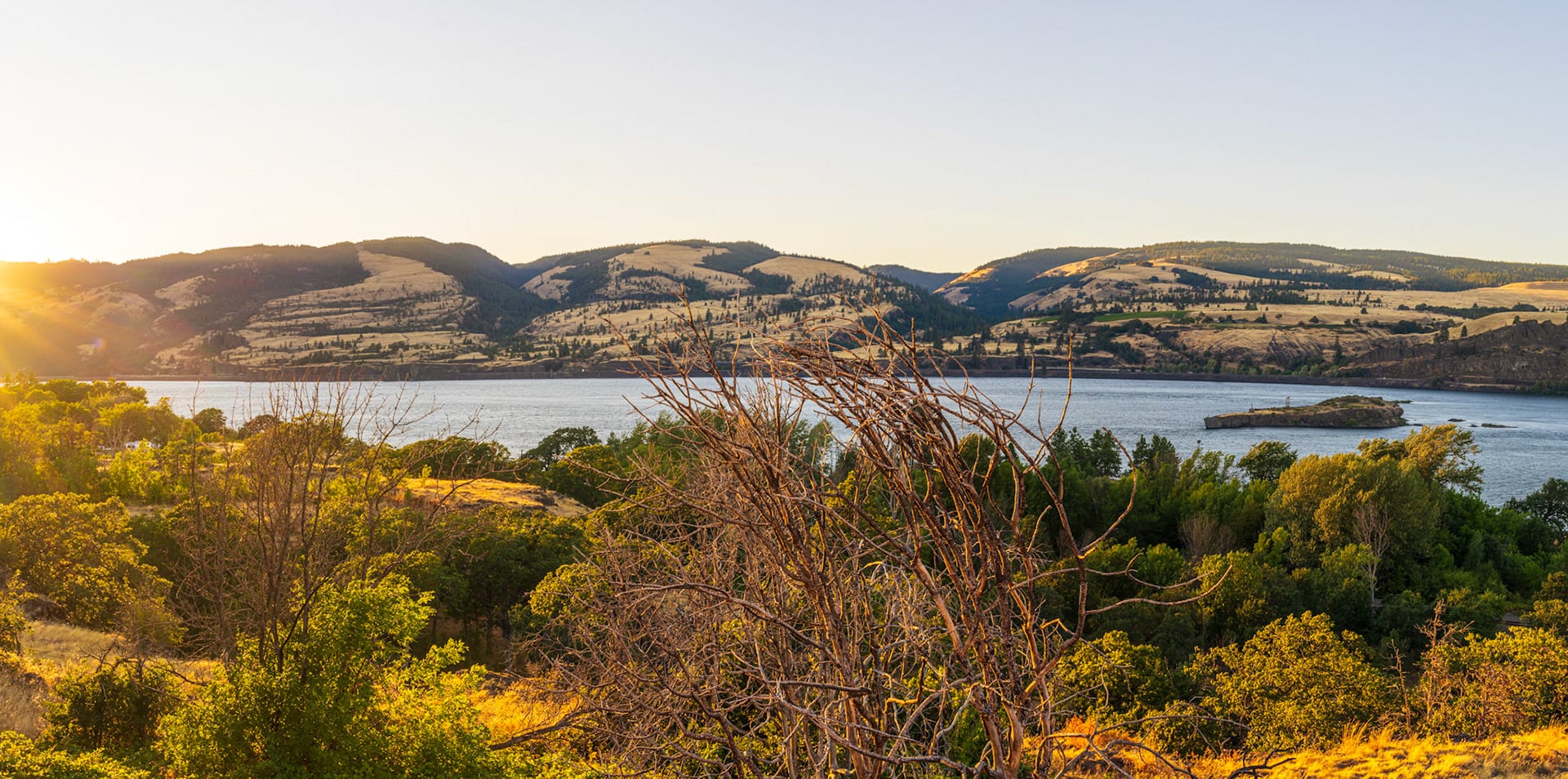 The gorge at golden hour, hazy hills and a bright band of light on the water.