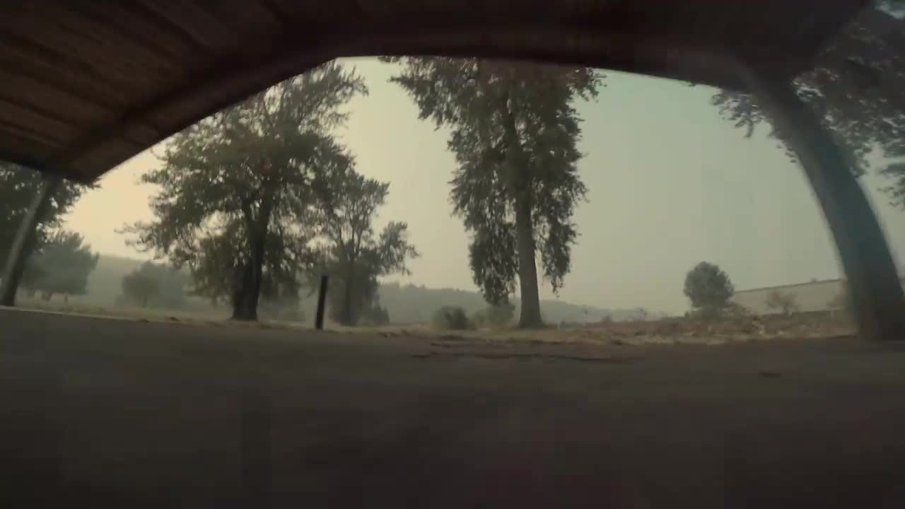 Flying out from under a highway underpass into an orange field of wildfire smoke.