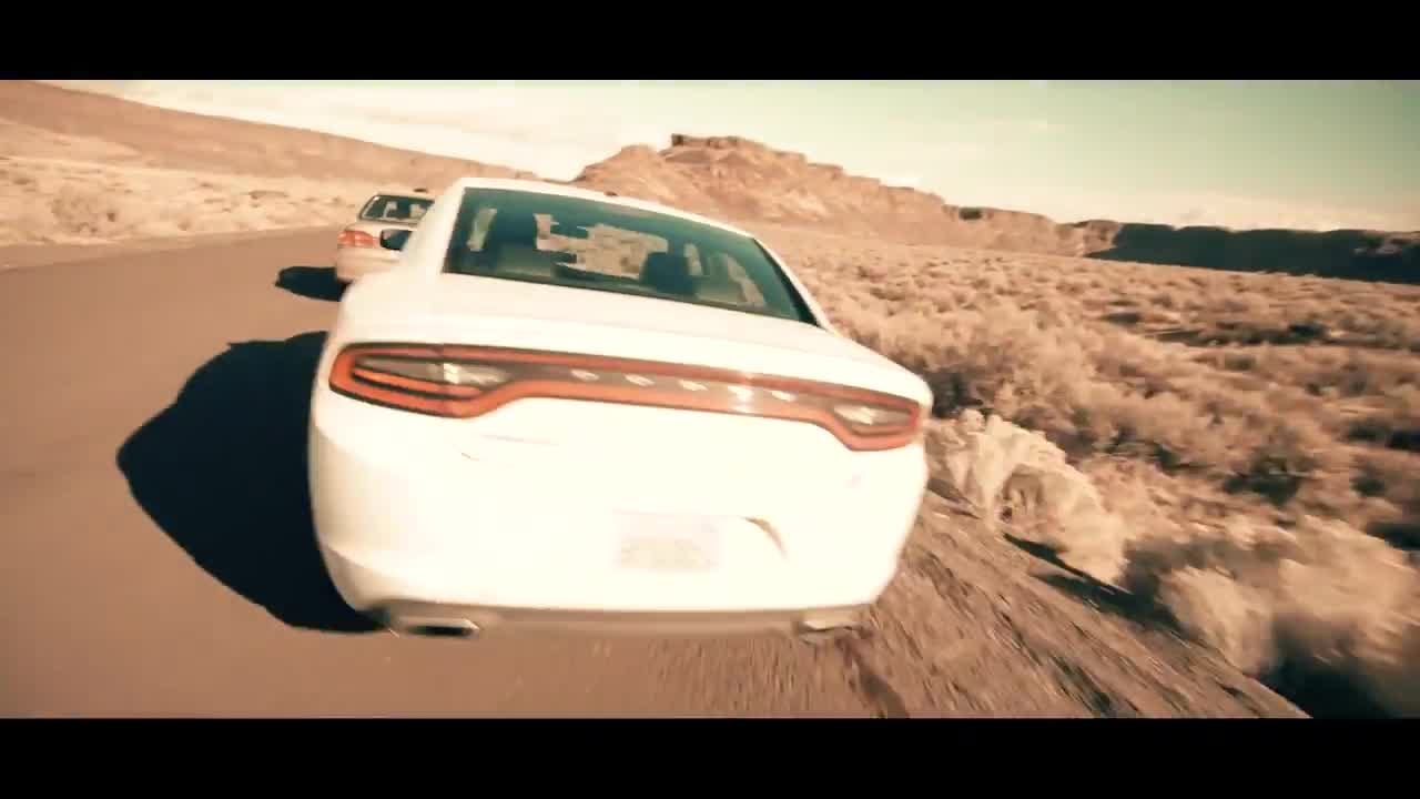 Chasing a white sedan as it kicks up dust on a desert road.
