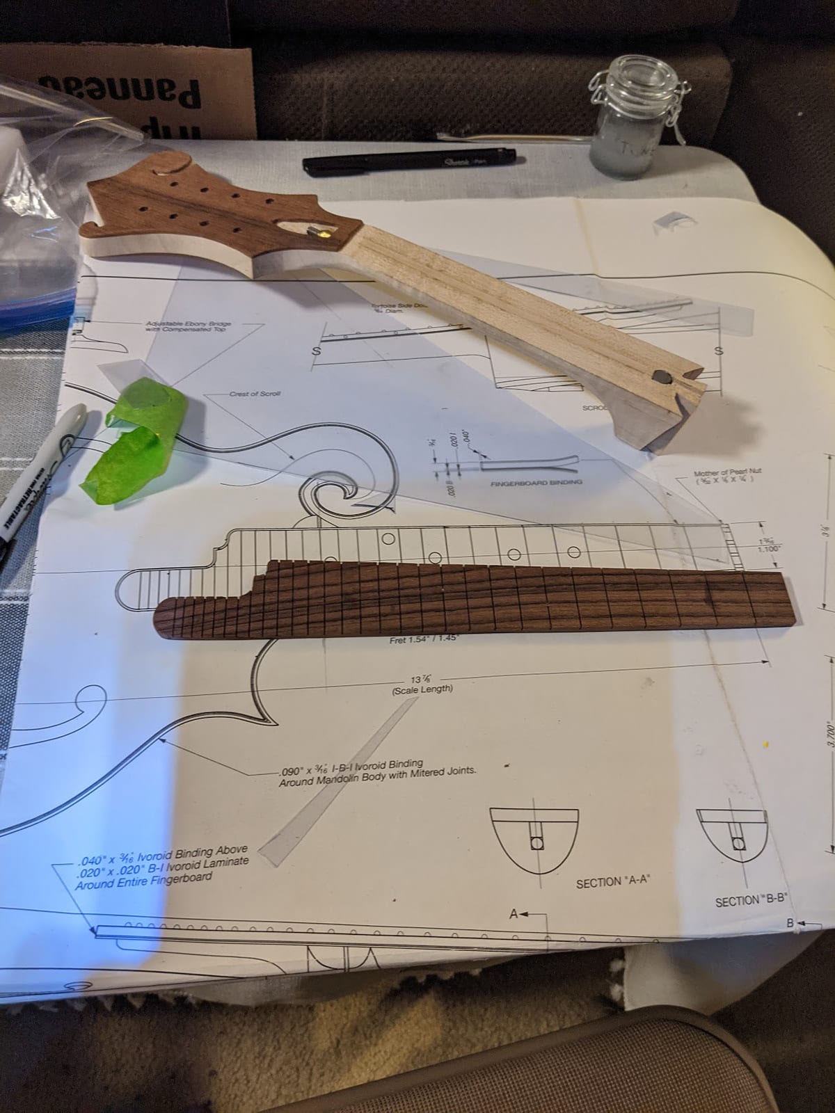 The blueprint spread out with the neck and the rosewood fretboard blank laid over it.
