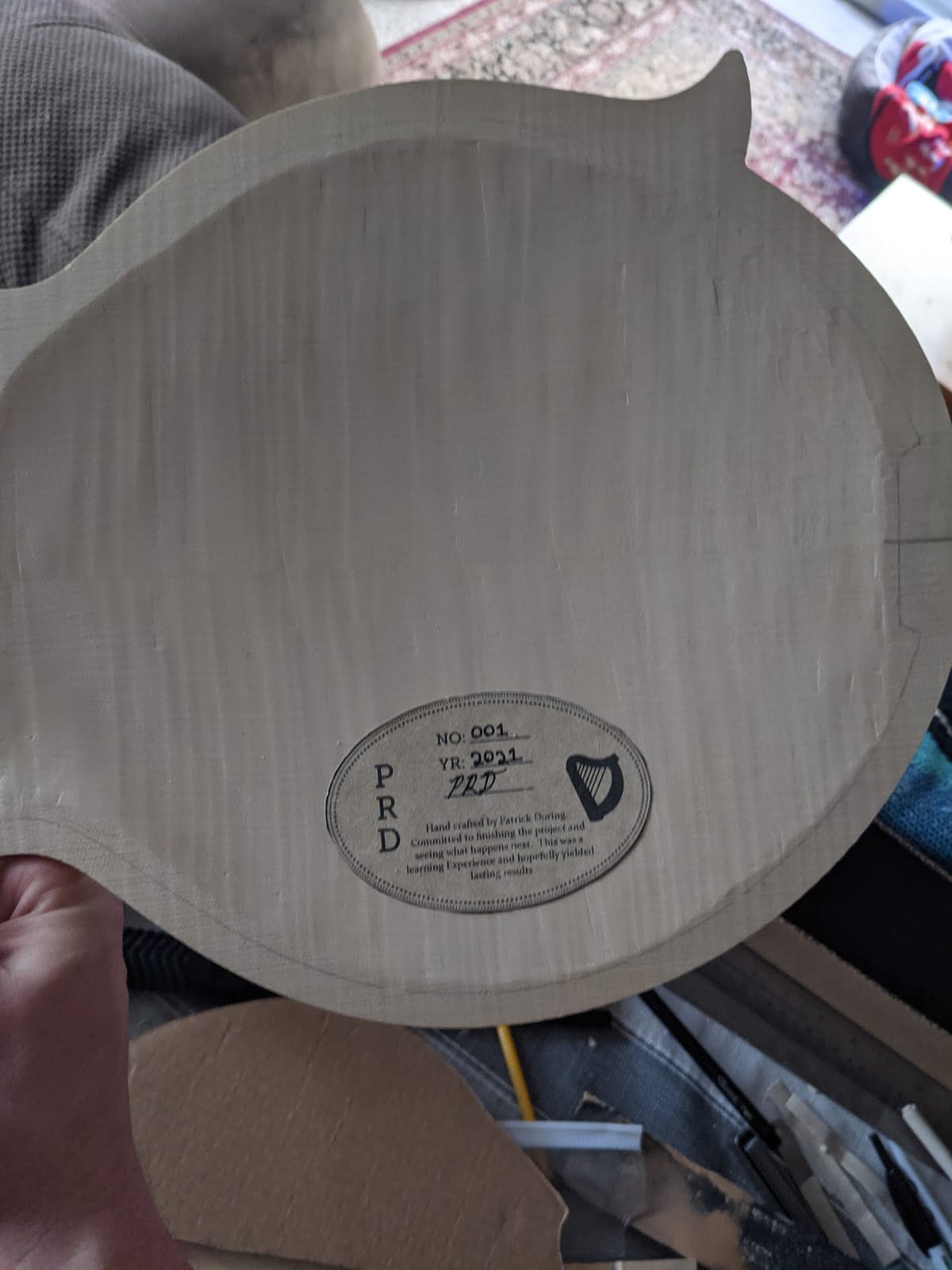The printed paper label glued inside the curly maple back, thinned and weathered so the ink sits into the wood.