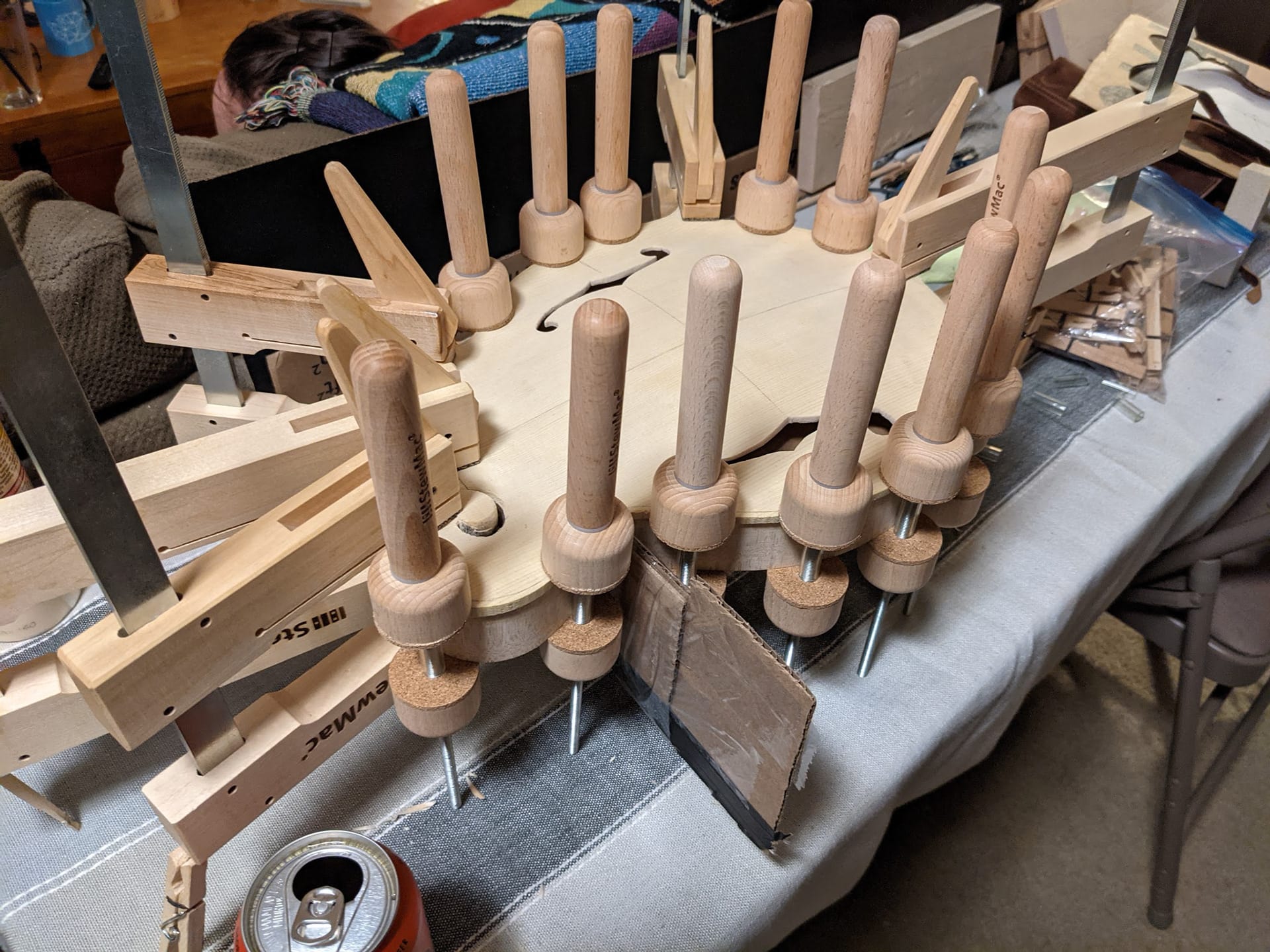 The body in a ring of wooden spool clamps on the folding work table while the top glue cures.