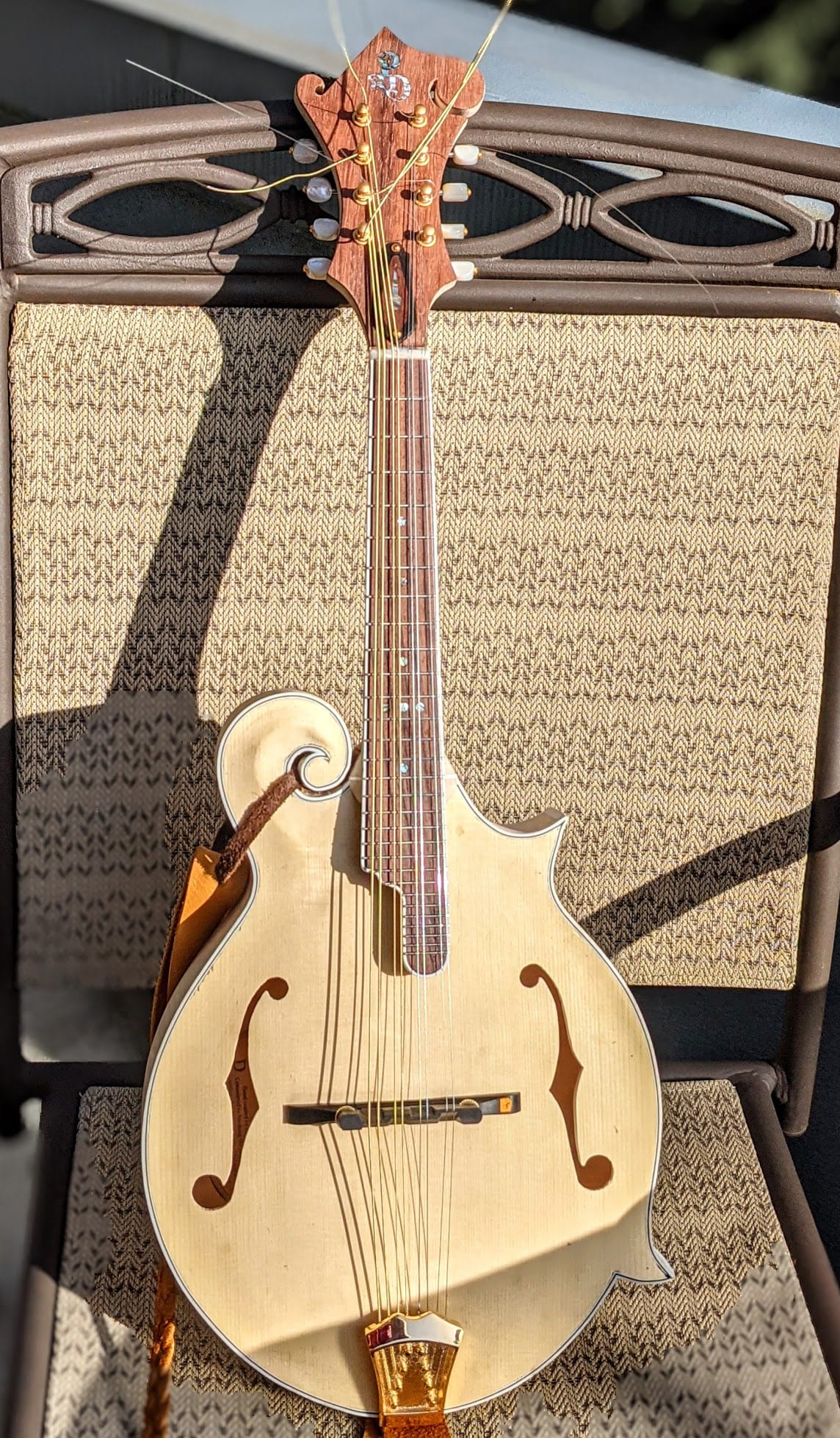 The finished raw instrument strung up and standing on a chair, the wood still pale.