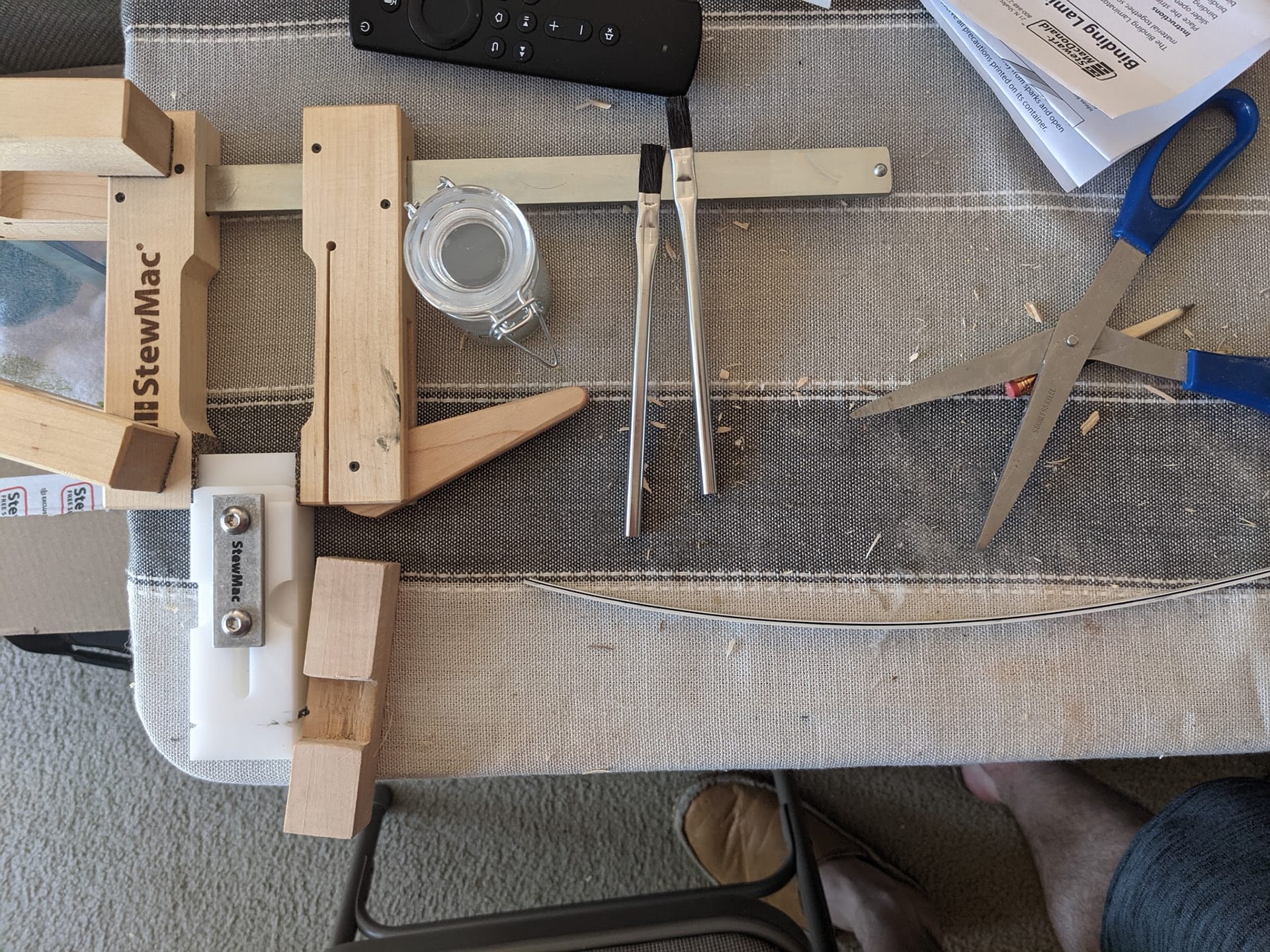 The lamination jig on the work table with a long strip of binding clamped up along its length.