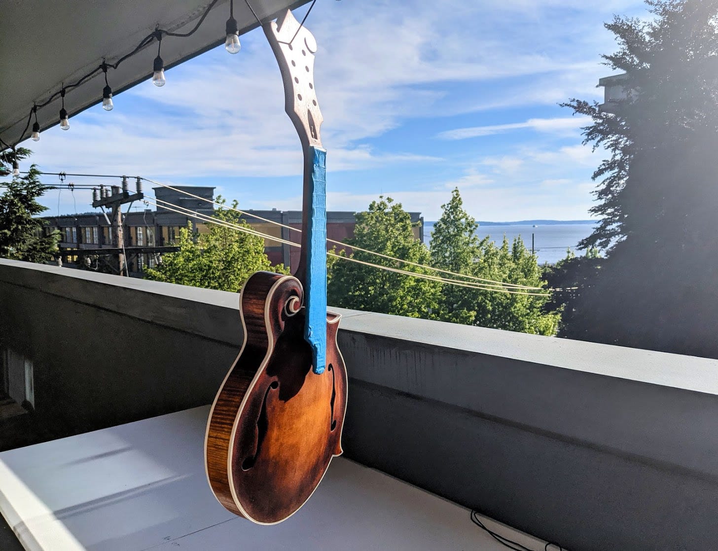 The instrument hanging from a bent wire hanger on the porch rail, waiting on a coat of lacquer.