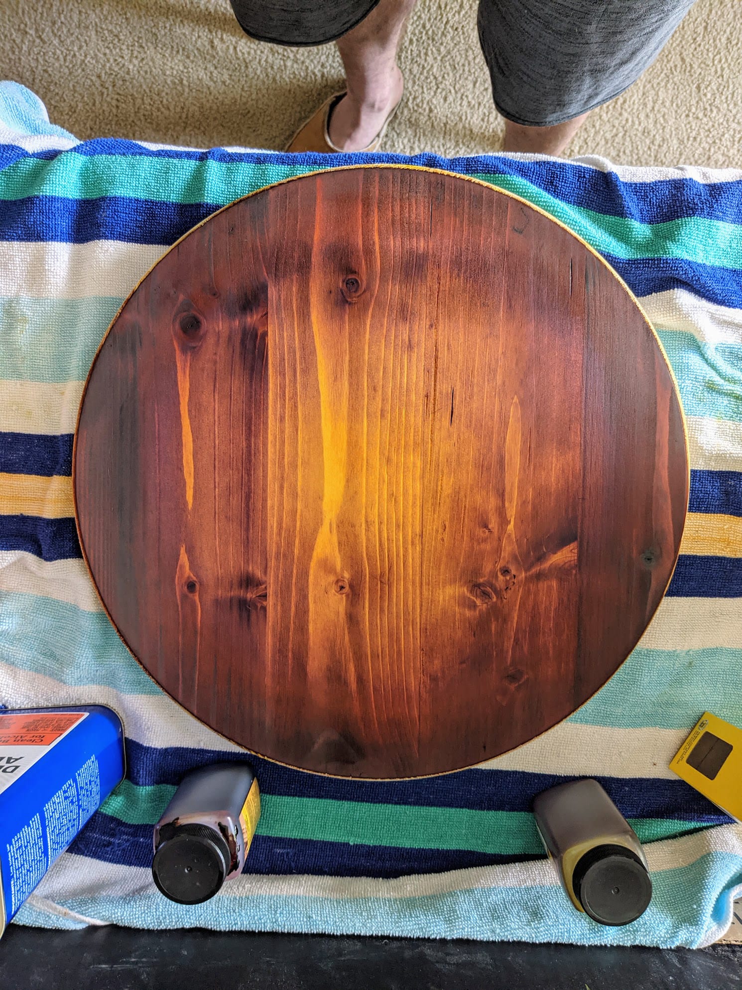The practice disc of spruce, sunbursted from a dark edge to an amber centre, on a striped towel.