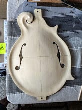 The spruce top with both f-holes cut and sanded, resting on a striped towel.