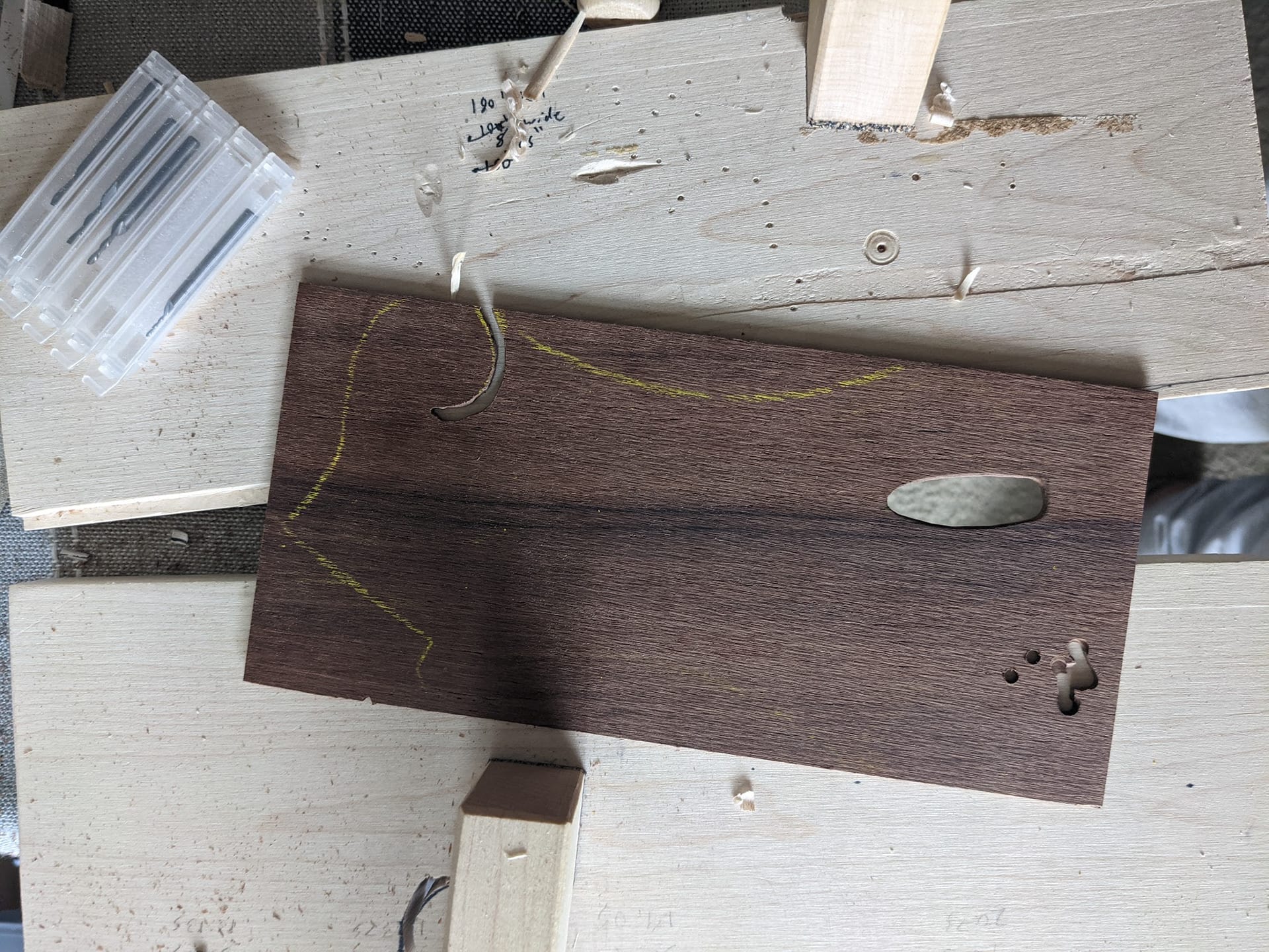 The rosewood veneer blank on a plywood backer with the truss rod cutout drawn onto it.