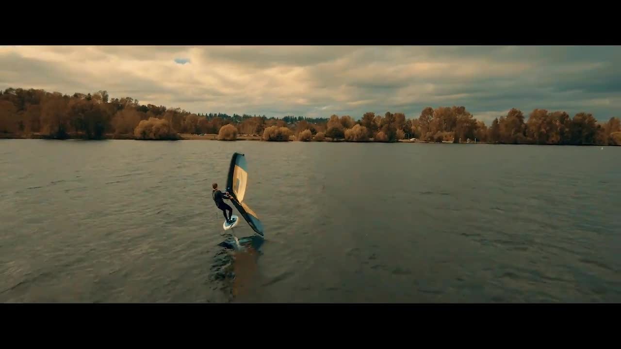 A rider out on the water with autumn colored trees along the far shore.